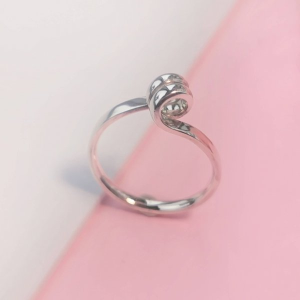Silver ring with swirl on top, photographed at an angle