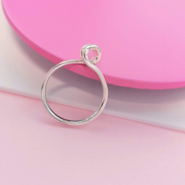 Silver ring with swirl on top, photographed standing up